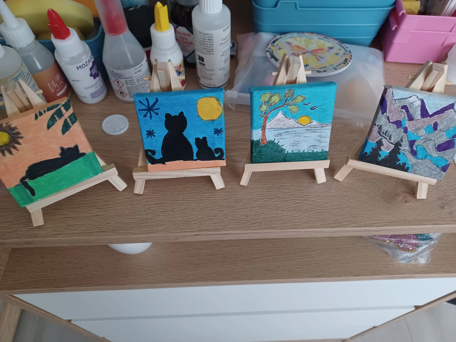 Vier handgeschilderde mini-schilderijtjes op houten ezels